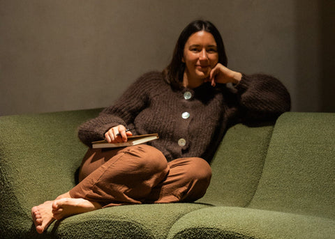 Annalise sitting on a green couch holding a book